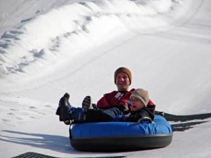 Father and child snow tubing, enjoying winter activities near Big Powderhorn.