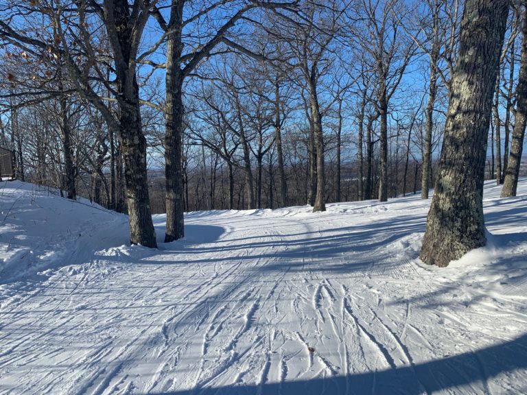 Snowy winter scene in Powderhorn Village with ski tracks and trees, perfect for Upper Peninsula winter lodging and recreation.
