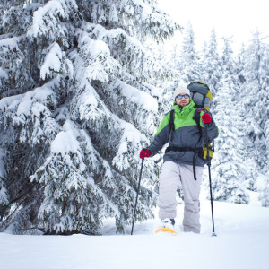 Man snowshoeing on winter trails near Big Powderhorn with snow-covered trees.