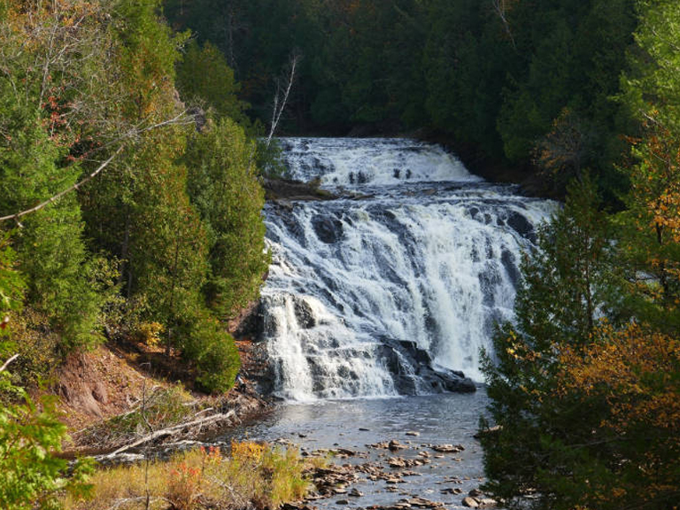 Scenic waterfall cascading over rocks in the Upper Peninsula, surrounded by autumn trees. Waterfalls near Big Powderhorn Mountain.