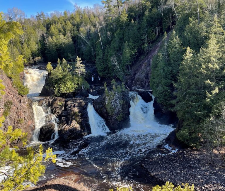 Waterfalls cascading through a rocky, forested area, a great spot for day trips near Big Powderhorn Mountain.