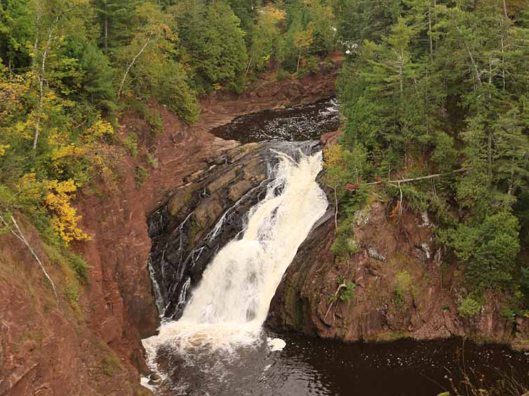 Scenic waterfall cascading down red rock cliffs in the Upper Peninsula. Waterfall near Big Powderhorn Mountain.