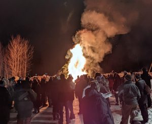 Crowd watches a bonfire at night near Big Powderhorn Mountain.