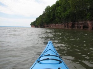 Kayaking on the water near sandstone cliffs, a popular Upper Peninsula paddling spot.