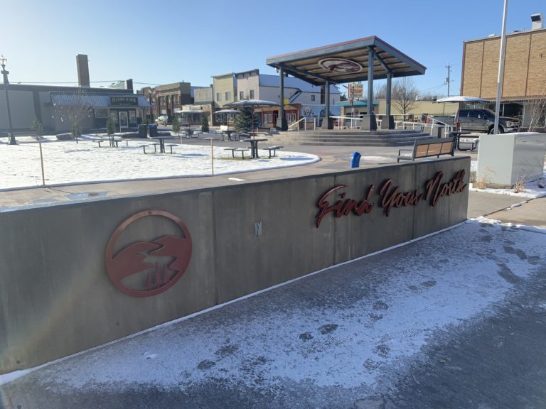 Find Your North sign in Powderhorn Village park, benches and gazebo in the background. Parks near Big Powderhorn Mountain.