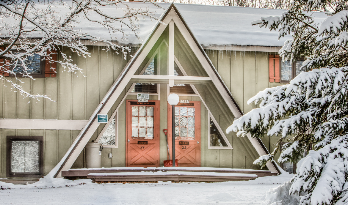 Snowy A-frame building with doors labeled "BEAR HUG 21" and "BEAR HUG 22".