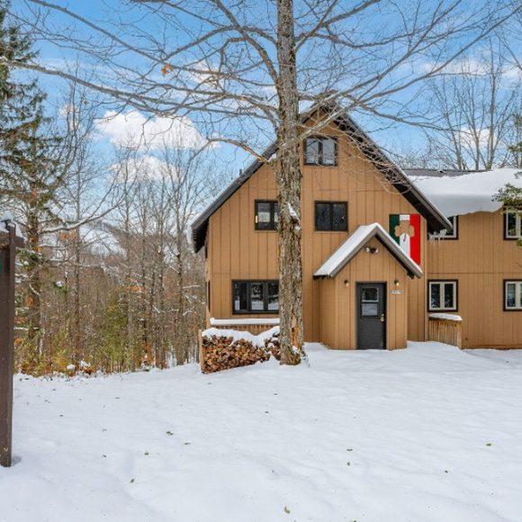 Celtic Haus sign and cozy cabin in a snowy forest setting.