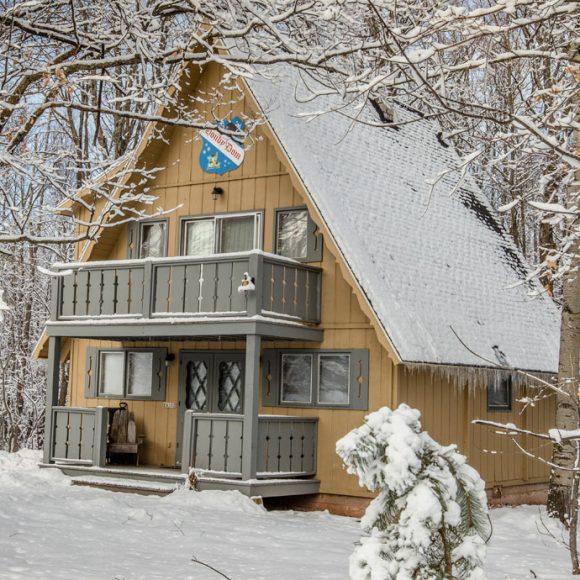 Snowy A-frame cabin in the woods. Winter scene.