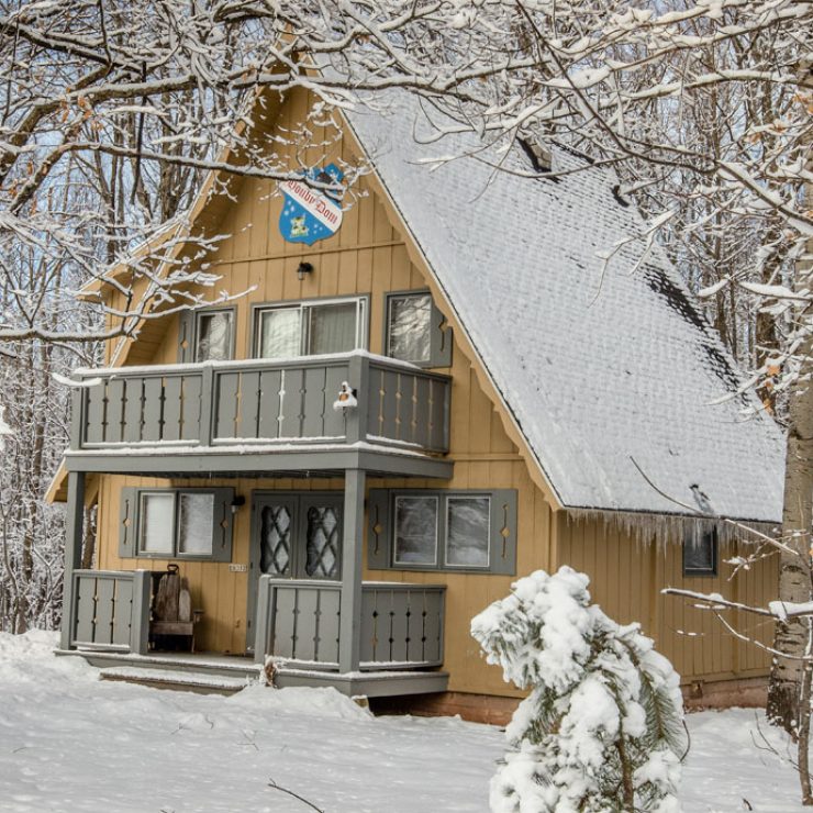 Snowy A-frame cabin in the woods. Winter scene.