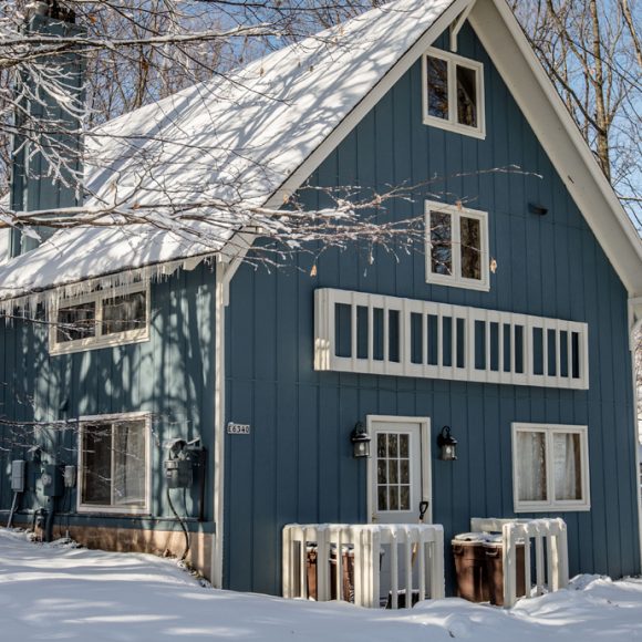 Snow-covered mountain house with icicles. Winter scene.