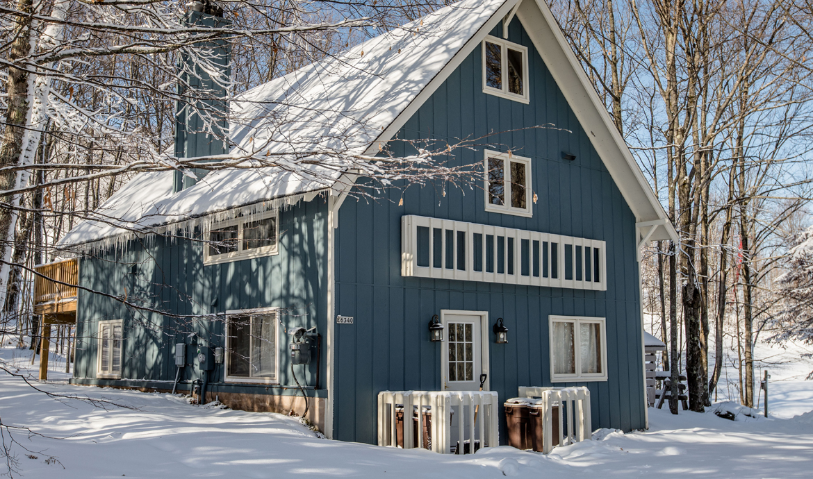 Snow-covered mountain house with icicles. Winter scene.