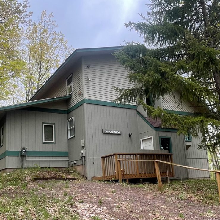 Exterior view of Snowbound cabin nestled among trees.