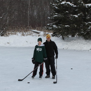 Father and son playing hockey on a frozen pond, a fun winter activity.
