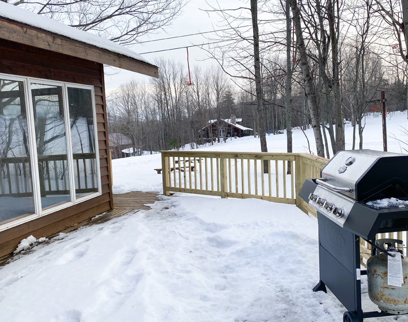 Snowy deck with grill at BEAR NECCESSITIES cabin, winter landscape