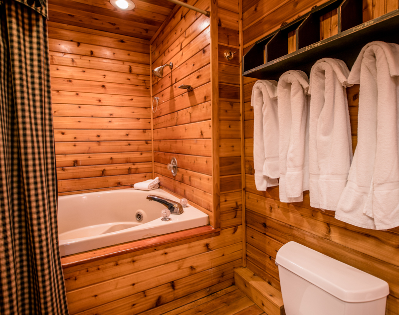 Cozy cabin bathroom with wood paneling, white towels, and a jacuzzi tub.