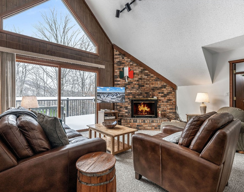 Cozy living room at Celtic Haus with fireplace, large window, and leather sofas