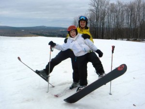Friends at a ski area near Big Powderhorn in the Upper Peninsula, one on skis, one on a snowboard.