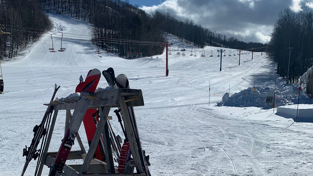 Snowy ski slopes with chairlifts and skis in the foreground, showcasing Upper Peninsula winter activities.