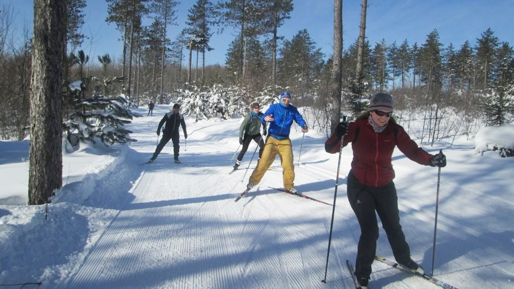 People cross-country skiing on a groomed trail in the Upper Peninsula during winter.