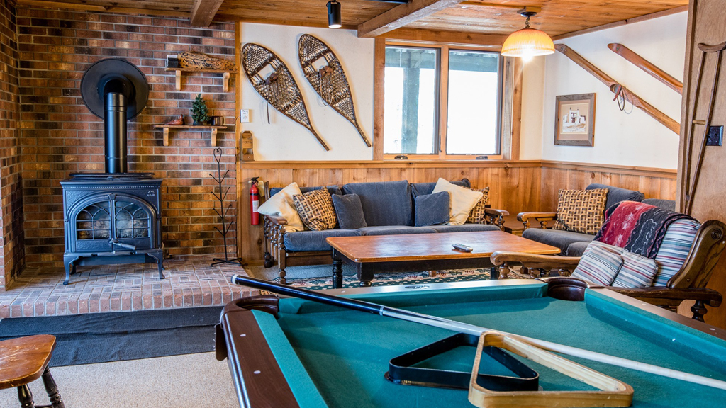 Cozy living room with pool table, fireplace, and snowshoes, perfect for Upper Peninsula winter activities.