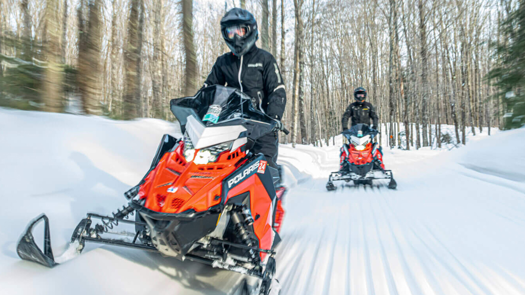 Two snowmobilers ride on a groomed trail near Big Powderhorn Lodging winter.